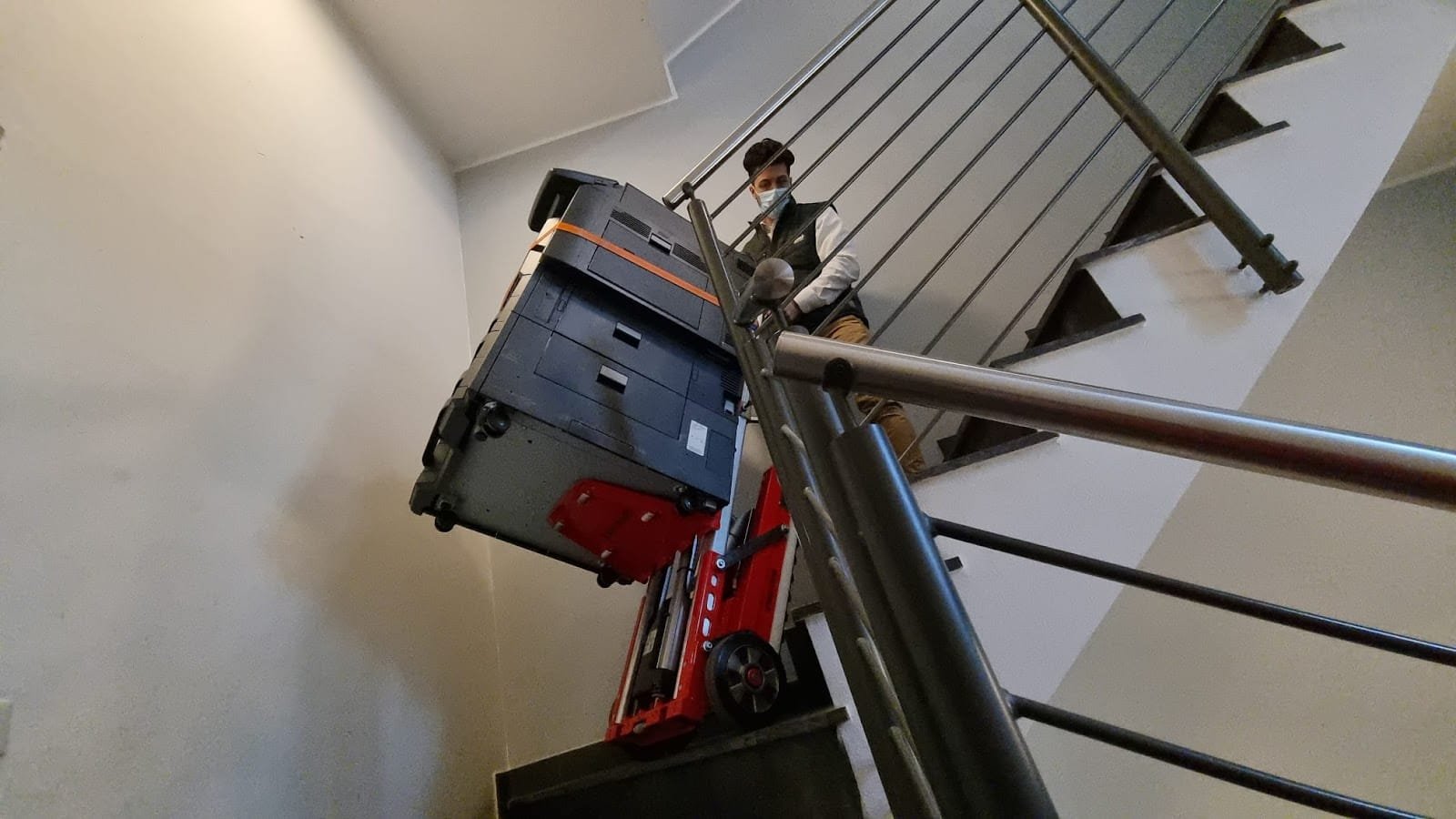 One transports a photocopier down stairs with an electric stair climber